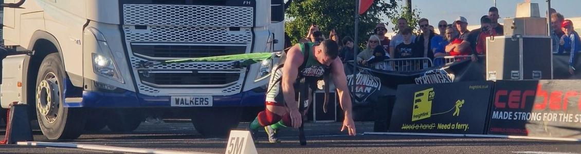 Man pulling truck with Freightlink banner behind at The UK Strongman 2024 Competition